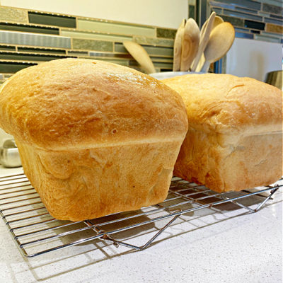 Two loaves of bread on a cooling rack.